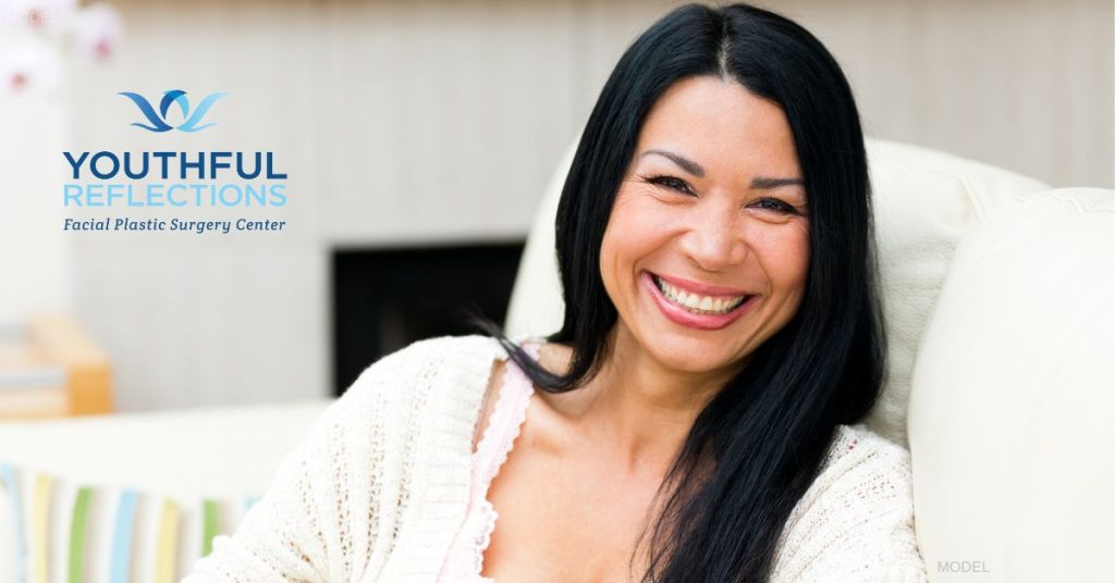 A woman with brown hair is sitting and smiling looking forward. (model)